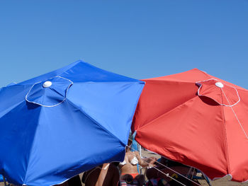 Low angle view of parasol against clear blue sky