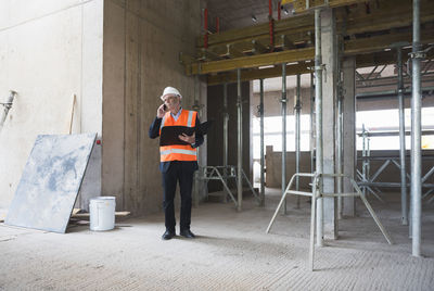 Man on the phone wearing safety vest in building under construction