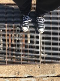 Low section of person standing on metal grate