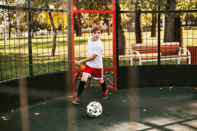 Full length of boy playing soccer in park