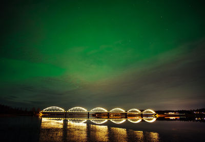 Illuminated bridge over river against sky at night