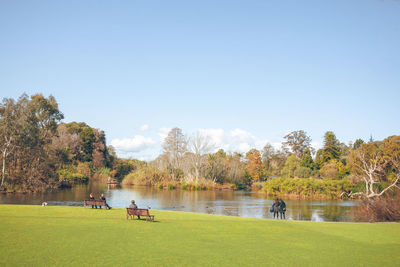 People by lake against sky