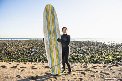 Long shot portrait of healthy asian woman going winter surfing