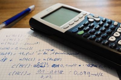 Close-up of calculator by text on paper over table