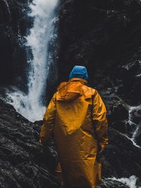 Rear view of man standing by waterfall