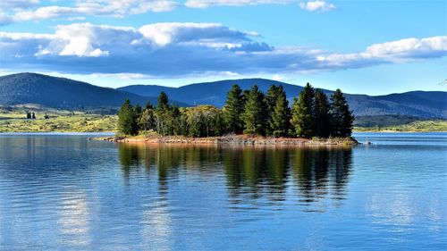 Scenic view of lake by trees against sky