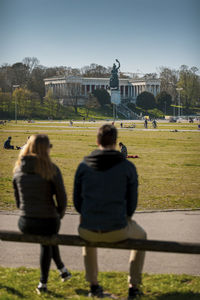 Rear view of people on grass against sky