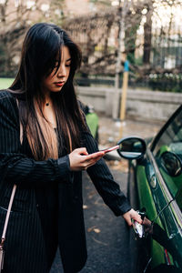 Full length of woman standing against car