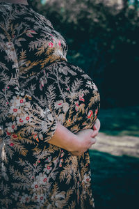 Midsection of pregnant woman standing outdoors