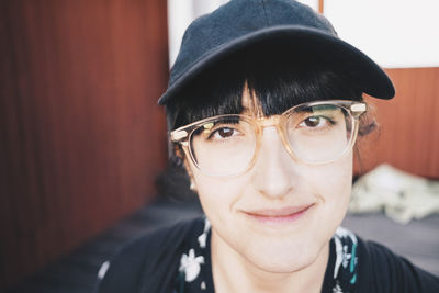 Close-up portrait of smiling woman wearing eyeglasses and baseball cap