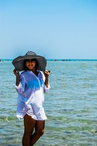 Young woman standing on beach against clear sky