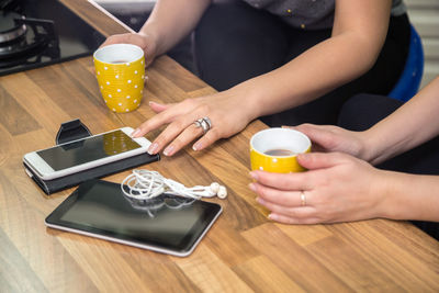 Midsection of woman holding coffee cup on table