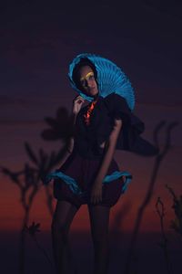 Low angle view of woman standing against sky at night