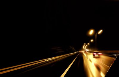 Light trails on road against clear sky at night