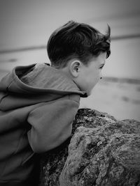 Side view of boy looking at rock