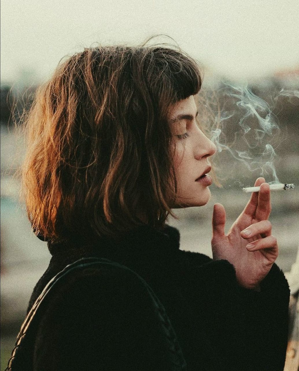 PORTRAIT OF WOMAN SMOKING CIGARETTE OUTDOORS
