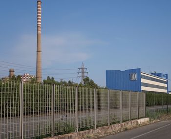 Built structure by fence against blue sky