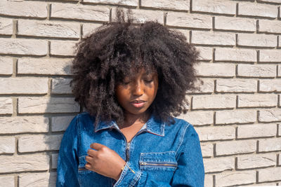 Portrait of woman standing against brick wall