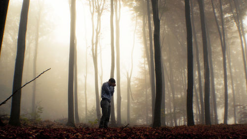 Depressed man standing in forest during foggy weather