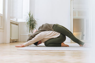 Attractive mother middle age woman and daughter teenager ptactice yoga together in bright room