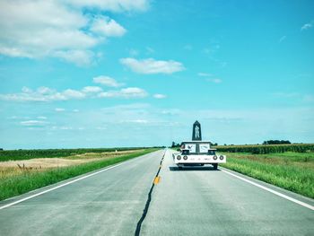 Parade float on country road against sky