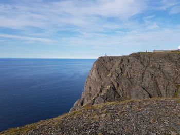 Rock formation by sea against sky