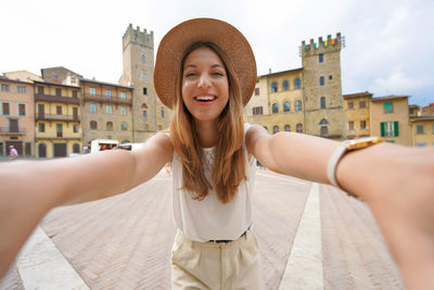 Smiling tourist girl in piazza grande square in the historic town of arezzo, tuscany, italy.