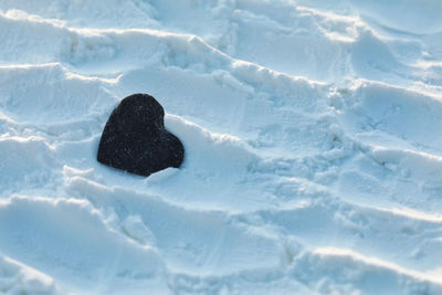 High angle view of black color shape of heart isolated on white texture background copy space. 