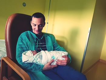 Smiling father carrying newborn baby at home