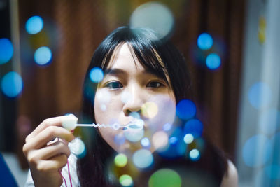 Young woman blowing bubbles at home