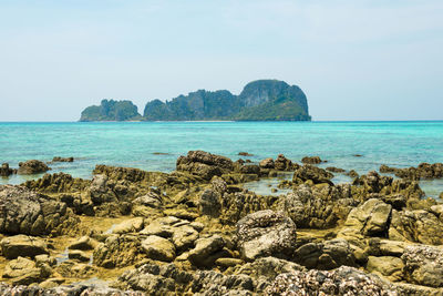 Tropical sea landscape with rocks at sand beach and rocky island at horizon