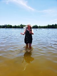 Full length of woman standing in water against sky