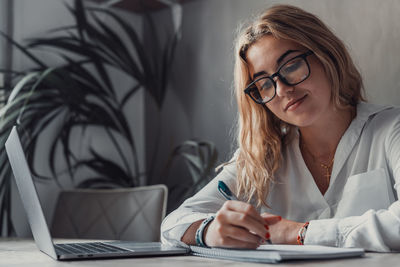 Young woman using mobile phone while sitting at home