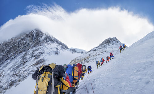 Panoramic view of people on snowcapped mountains against sky