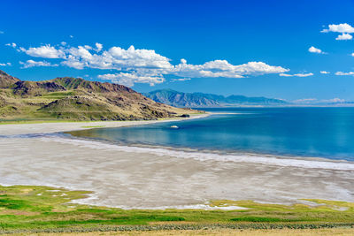 Scenic view of sea and mountains against blue sky