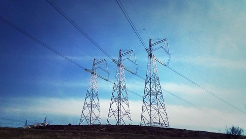 Low angle view of electricity pylon against blue sky