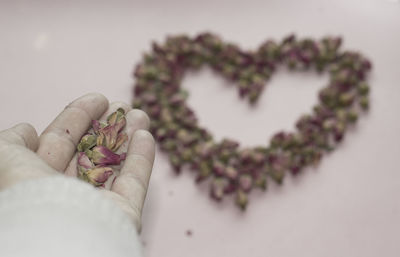 Cropped hand making heart shape with petals