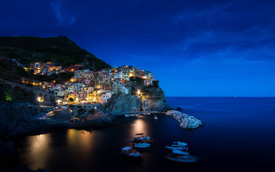 Illuminated townscape by sea against sky at night