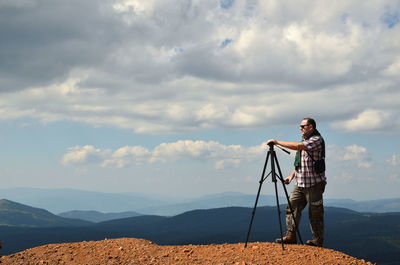 Man standing on mountain high preparing to shoot a wonderful landscape