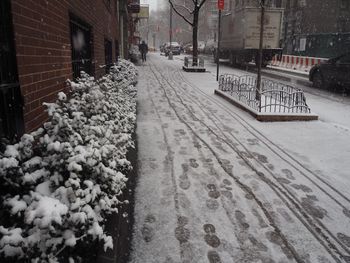 Snow covered street amidst buildings in city