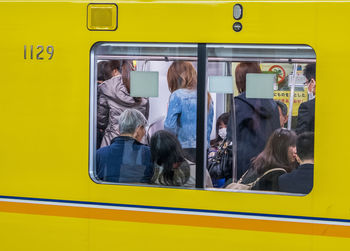 People in yellow train seen through window