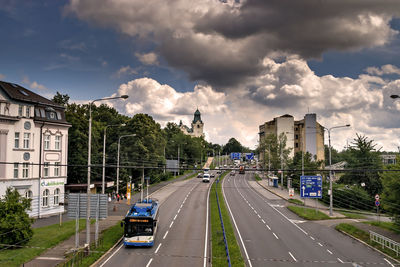 Vehicles on road amidst buildings in city against sky