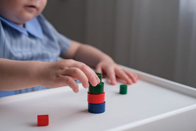 One year old child plays with wooden figurines. development of fine motor skills of kids