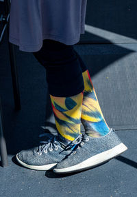 Colorful patterned socks on woman wearing grey tennis shoes and dress
