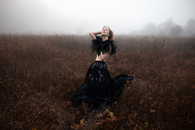 Woman standing on field during foggy weather