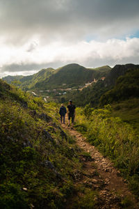 Rear view of people walking on trail against sky