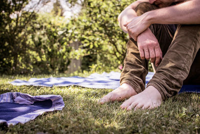 Low section of man sitting on grassy field