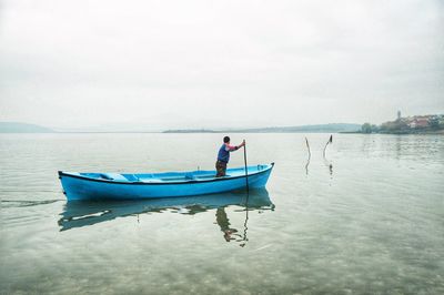 Man in boat on sea against sky