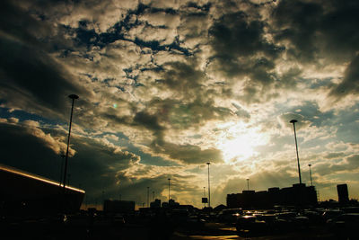 Vehicles on road against cloudy sky