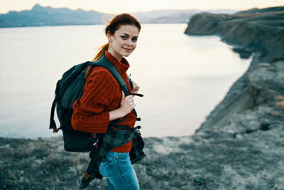 Portrait of smiling young woman standing on shore